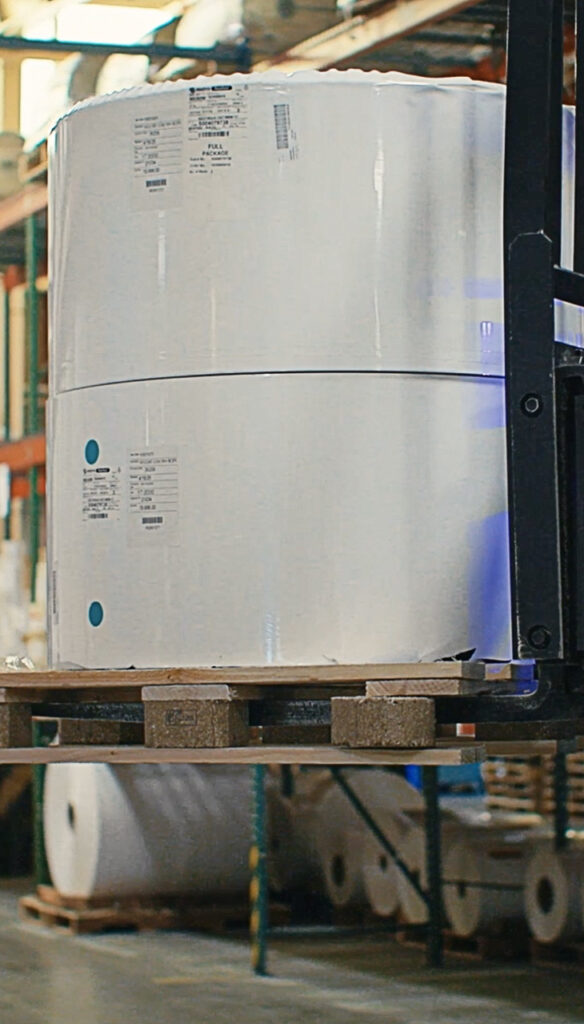 Forklift moving a large roll of blank labels. Blank labels are used for thermal transfer and printing.